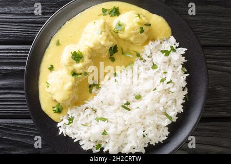 Popular Danish family dish boller i karry or meatballs in curry sauce with rice close up in the plate on the table. horizontal top view from above Stock Photo