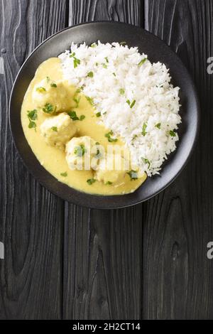 Boller i Karry Pork Meatballs in mild Curry with rice close up in the plate on the table. Vertical top view from above Stock Photo