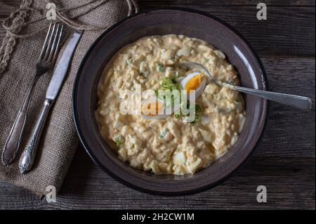 Egg salad fresh and homemade cooked in a brown enamel bowl on wooden table Stock Photo