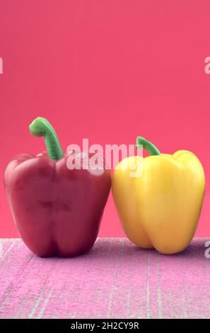 Colorful pastel purple, yellow bell peppers composition on pink grunge cement against pink background. Stock Photo