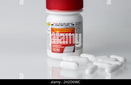 bottle of Tylenol eight hour extended release acetaminophen pain reliever caplets with pills in front on a white reflective background with copy space Stock Photo