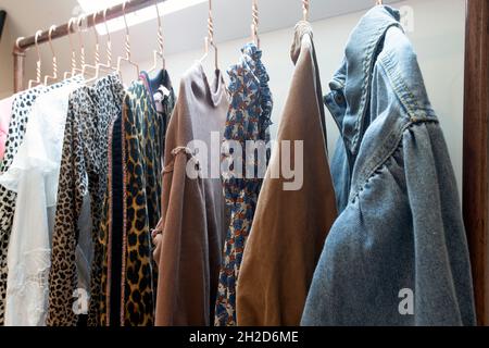 Hangers on rack with colorful stylish fashion clothes in modern room. House interior, fashion and storage concept Stock Photo