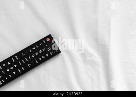 Black TV remote on a bed in a hotel. Stock Photo