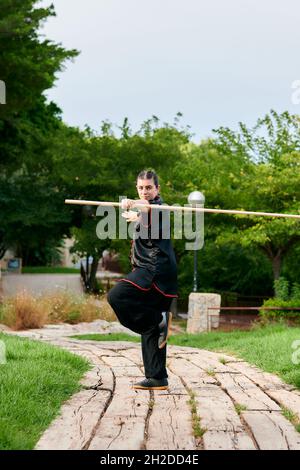 Woman in uniform practicing martial arts with a stick Stock Photo