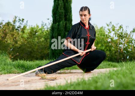 Woman in uniform practicing martial arts with a stick Stock Photo