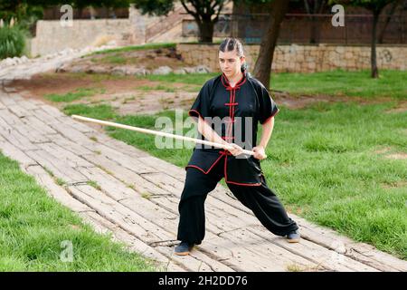 Woman in uniform practicing martial arts with a stick Stock Photo