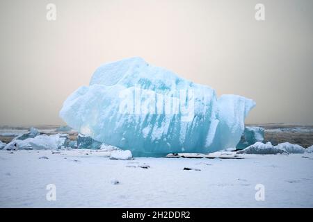 Spectacular view of iceberg piece on snowy coast against endless ocean under light sky in Iceland Stock Photo