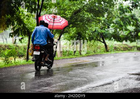 People riding a motorcycle on a rainy day Stock Photo