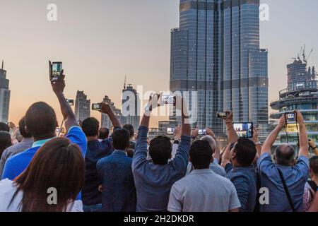 DUABI, UAE - MARCH 10, 2017: Crowds of people observe The Dubai Fountain and Burj Khalifa skyscraper. Stock Photo