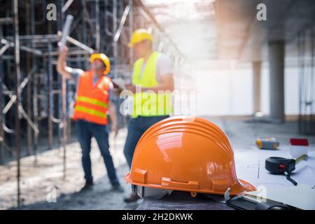 The yellow safety helmet in construction site and construction site worker background safety first concept. Stock Photo