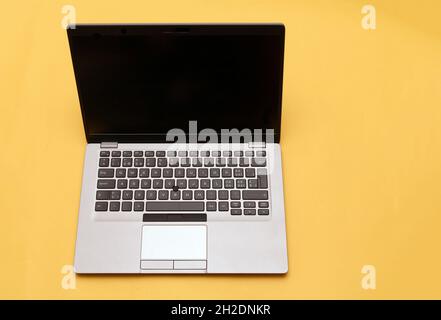 Open modern PC laptop with empty black screen on yellow background Stock Photo
