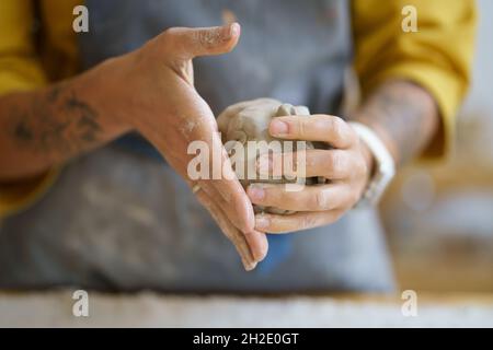 Female potter artist hands molding raw clay. Woman ceramist in apron prepare for shaping pottery Stock Photo