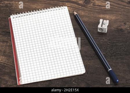small spiral notepad with copy space, pencil and sharpener on wooden table Stock Photo
