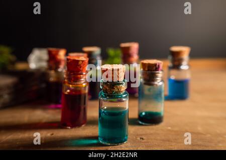 Close-up image of a small glass stopper bottle filled with blue liquid. Within the background other small bottles filled with various colored liquids. Stock Photo