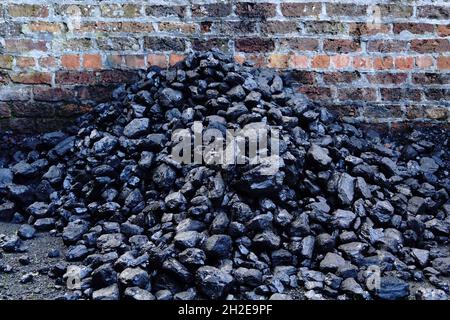 Stack of coal against red brick wall Stock Photo