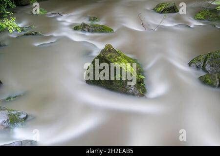 abstract image of a bright green rock in blurred flowing water Stock Photo