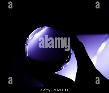 Closeup of a person's hand holding a reflective crystal ball Stock Photo