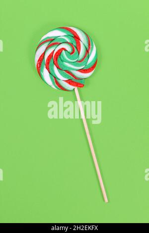 Lollipop with Christmas colors on green background Stock Photo