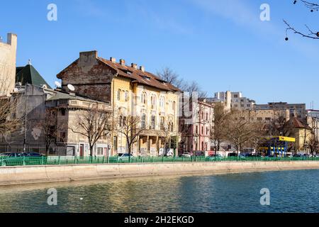 Bucharest, Romania, 13 February 2021 - Landscape with large old trees and old buildings near Dambovita river and clear blue sky in the center of Bucha Stock Photo