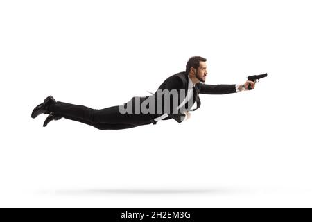 Full length profile shot of a man in a suit flying and holding a gun isolated on white background Stock Photo