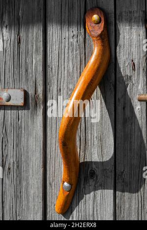 handcrafted orange wooden handle, on old wooden door Stock Photo