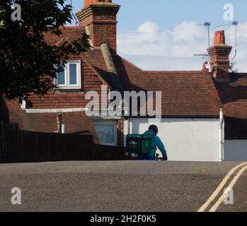 Uber Eats delivery driver seen with a large delivery box on his back when cycling down a hill during the day in October 2021. Stock Photo