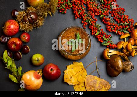 Zucchini cream on the  background decorated with   wild berries,  chestnuts , pomegranate  and autumn leaves, colorful autumn flat lay. Stock Photo