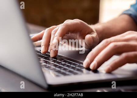 Closeup view on male hand typing on laptop computer keyboard at workplace Stock Photo