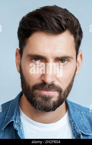 Closeup face portrait of bearded man isolated on blue studio background Stock Photo