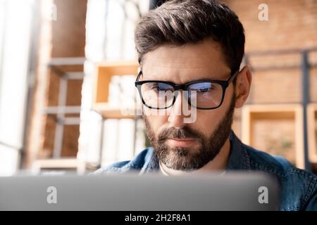 Closeup focused businessman wearing computer glasses looking at laptop screen Stock Photo