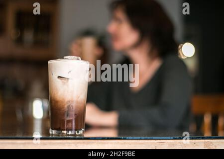 Drinking iced coffee at the table with middle age white woman Stock Photo