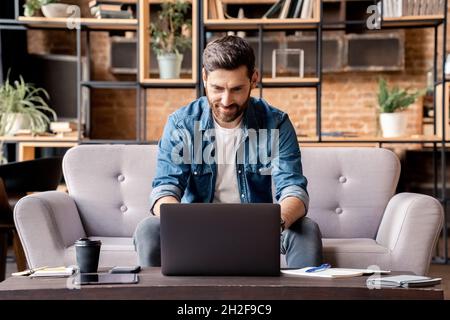 Handsome smiling caucasian man freelancer using laptop at home in living room Stock Photo