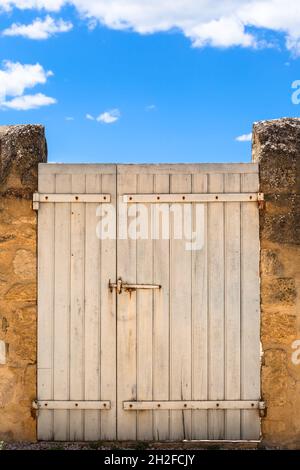 Shabby white door at an exterior wall under blue sky (copy space) Stock Photo
