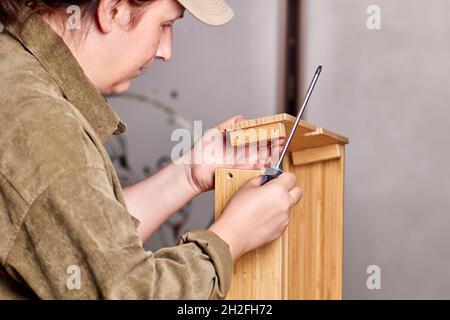 Assembler is installing drawer of flat pack furniture using tool. Stock Photo