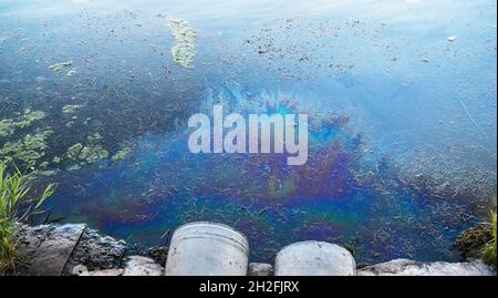 Toxic oil or petroleum pollution of ocean or river water from waste water pipe. Stock Photo