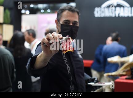 Madrid, Spain. 20th Oct, 2021. An exhibitioner shows Spanish ham in Feria de Madrid in Madrid, Spain, on Oct. 20, 2021. The 34th Salon Gourmets was held here from Oct. 18 to 21. Credit: Gustavo Valiente/Xinhua/Alamy Live News Stock Photo