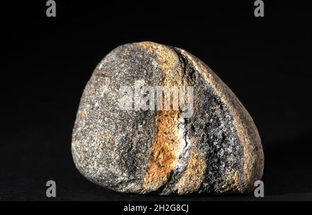 Single stone with red and brown geological pattern isolated on black background Stock Photo