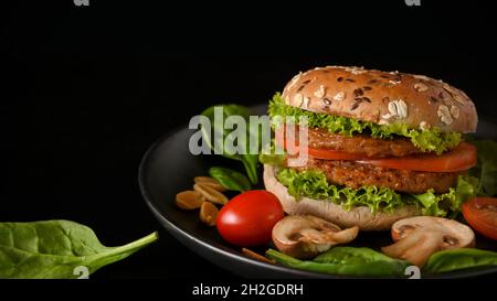 Plant based burger with fresh and organic vegetables on a plate in black background. Healthy food concept Stock Photo
