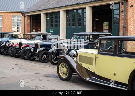 Vintage Alvis cars outside a workshop at the Bicester Heritage Centre super scramble event. Bicester, Oxfordshire, England Stock Photo