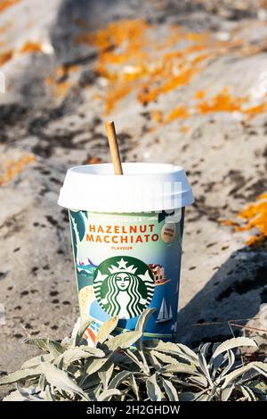 Kemerovo, Russia - 17 October 2021: Starbucks to go coffee cup on scenic nature background. Hazelnut macchiato coffee paper cup, close-up. Stock Photo