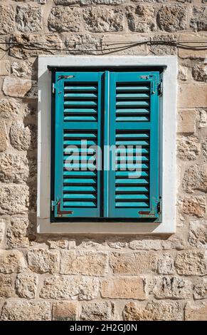 Old window with closed shutters on exterior wall. Stock Photo