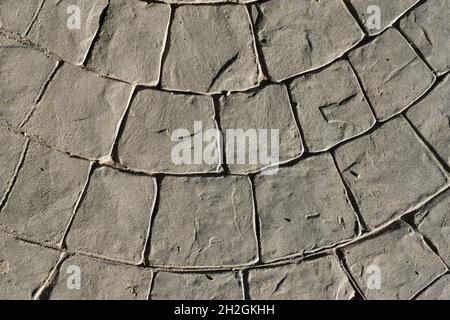 Gray stamped concrete pavement outdoor, mimics cobblestones circular pattern with waves, flooring exterior, decorative paving cobble stone Stock Photo