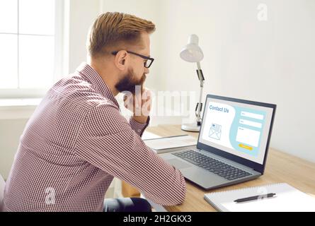 Man sitting and thinking what to write in Contact Us form on landing page website Stock Photo