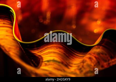 Selective focus on yellow edge of black and orange curly glass bowl. Stock Photo