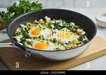 Green shakshouka. Fried in pan. Eggs, parsley, celery, spinach, sheep cheese, pepper Stock Photo