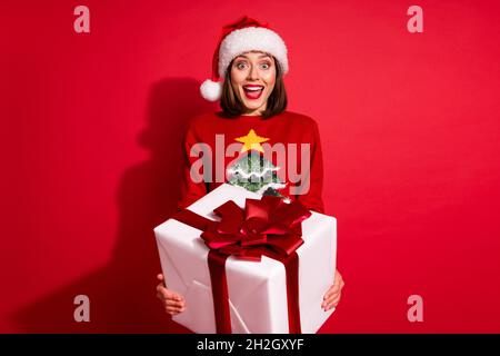 Photo of sweet impressed young woman wear ornament sweater giving christmas gifts isolated red color background. Stock Photo