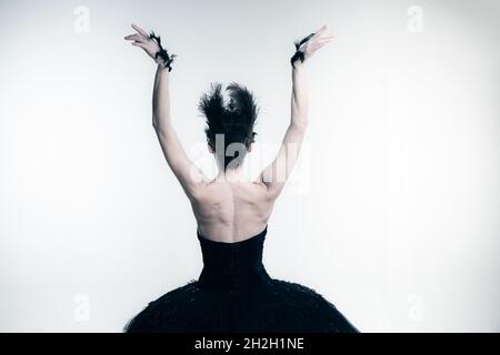Back view of young ballerina wearing black tutu, stage dress posing isolated on white studio backgorund Stock Photo