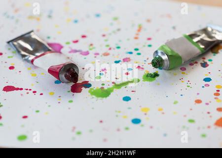two tubes with paint on white cardboard with various color blobs and paint splatters Stock Photo