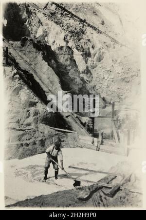 Bloomdale China Clay and Stone Works, St Stephen-in-Brannel, Cornwall, 1919-1936. A man shovelling sand in one of the sand pits at Bloomdale China Clay and Stone Works. This photograph forms part of a set within the album documenting the china clay industry of Cornwall, particularly focusing on the area around St Austell. China clay - also called kaolin - was used to make porcelain. The china clay industry was one of the main extractive industries in Cornwall. The images are accompanied by handwritten notes and descriptions of the processes involved in the production of china clay. Together th Stock Photo