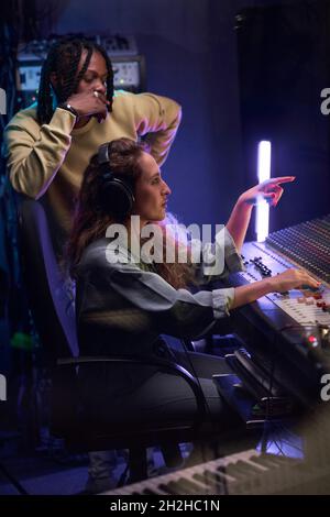 Two musicians writing music in team using music keyboard in the recording studio Stock Photo